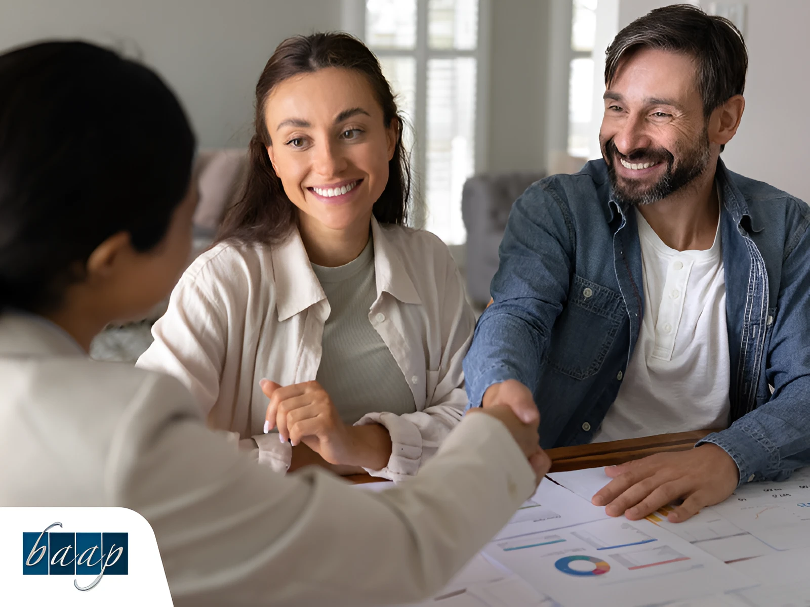 Smiling couple shaking hands with advisor during a meeting